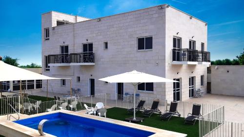 un edificio con piscina, sillas y sombrillas en אשתורי - ASHTORI, en Beit She'an