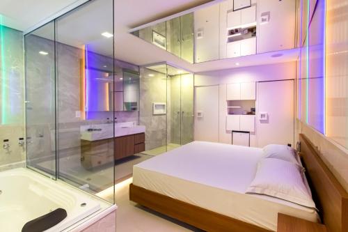 Uno Prime Motel - Aricanduva في ساو باولو: غرفة نوم مع دش وسرير وحوض استحمام
