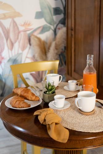 a table with plates of croissants and cups of orange juice at BOTANIC GUESTHOUSE ESTE in Este