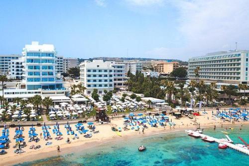 a beach with chairs and umbrellas and people in the water at Silver Sands Beach Hotel in Protaras