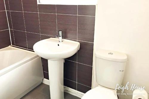 a bathroom with a white sink and a toilet at Leigh Accommodation in Leigh