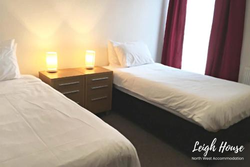 two beds in a room with two lamps on a night stand at Leigh Accommodation in Leigh