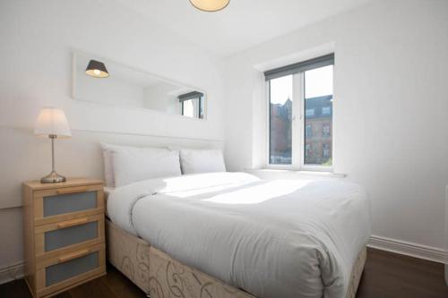 a white bedroom with a large bed and a window at Grand Canal District Apartments in Dublin