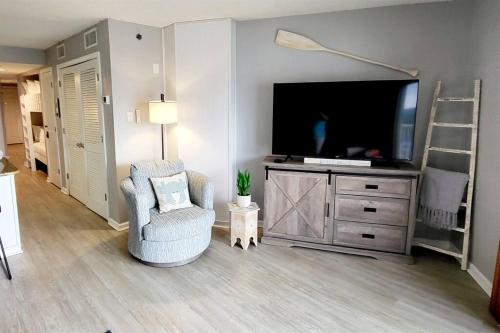 ein Wohnzimmer mit einem TV und einem Stuhl in der Unterkunft Tradewinds 808 - NEW Rental- 1bd/2bath-Luxury Comfort in Orange Beach