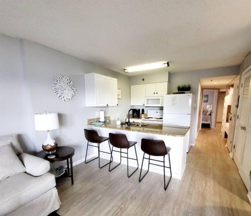 eine Küche und ein Wohnzimmer mit einer Theke und Stühlen in der Unterkunft Tradewinds 808 - NEW Rental- 1bd/2bath-Luxury Comfort in Orange Beach