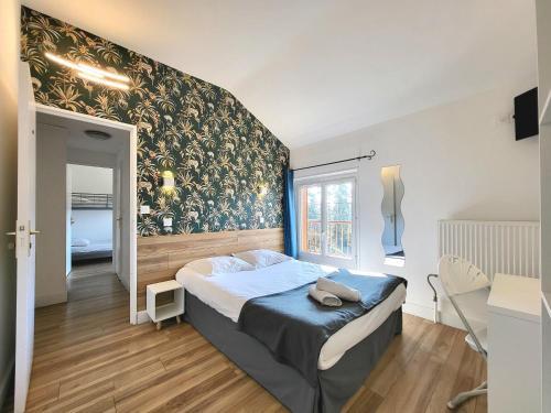 1 dormitorio con cama y pared con papel pintado en Cit'Hôtel La Résidence en Villebois