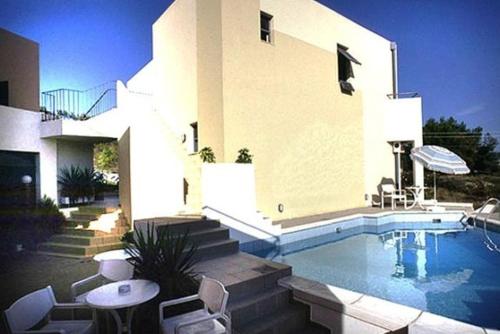 a house with a swimming pool in front of a house at Blue Sky Hotel Apartments in Tolo