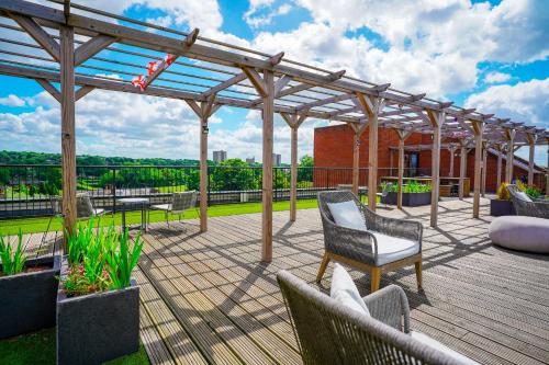 a deck with chairs and a pergola on a building at Spacious Luxury Apartment in Stevenage, Sleeps 6, with Free Parking, and Free Wi-Fi in Stevenage