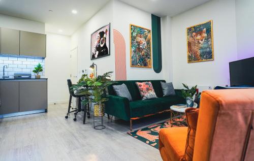 a living room with a green couch and a kitchen at Spacious Luxury Apartment in Stevenage, Sleeps 6, with Free Parking, and Free Wi-Fi in Stevenage