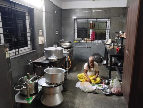 un hombre sentado en el suelo en una cocina en SRY Comfort Residence, en Bangalore