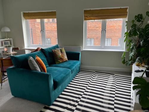 a blue couch in a living room with two windows at The Flat on Humber Street in Hull