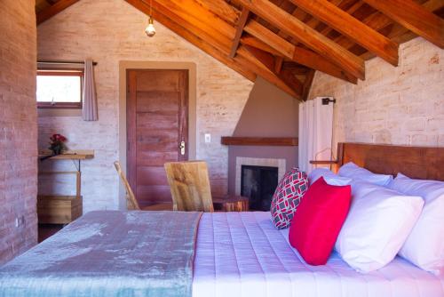 a bedroom with a bed with red pillows and a fireplace at Pousada Alpes da Mantiqueira in Monte Verde