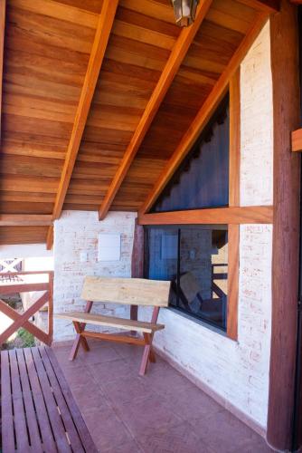 a wooden bench sitting on the porch of a building at Pousada Alpes da Mantiqueira in Monte Verde