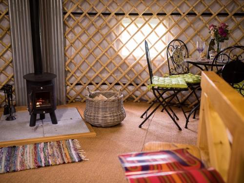 a room with a wood stove and a table and chairs at 'Villager' the Yurt at Pentref Luxury Camping in Penuwch