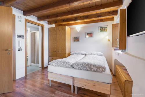 1 dormitorio con 1 cama en una habitación con techos de madera en Monolocali di Cà Selvetta Holiday Houses, en Morbegno