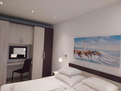 a bedroom with a bed and a desk and a painting on the wall at Dream View apartment in Cres
