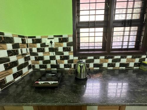 a kitchen counter with a coffee pot on a counter top at ISHRA SERVICE APARTMENTS in Dharmastala