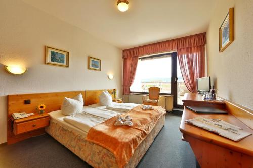 a hotel room with a large bed and a desk at Der Wolfshof - Dein Zuhause im Harz in Langelsheim