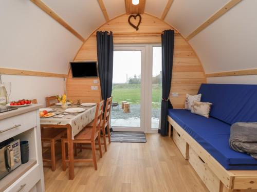 Habitación pequeña con cama azul y mesa de comedor. en Bevy en Harpham