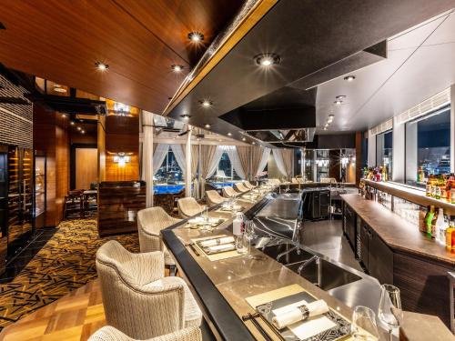 a restaurant with a long bar with chairs at APA Hotel & Resort Ryogoku Eki Tower in Tokyo