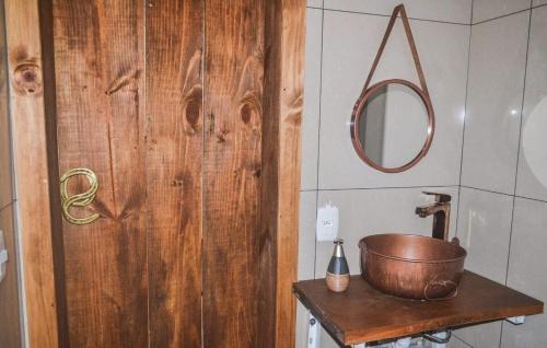 uma casa de banho com uma porta de madeira e uma panela de cobre sobre uma mesa em RECANTO DO SINALEIRO GRAMADO em Gramado