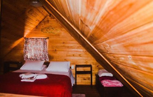 um quarto com uma cama num chalé de madeira em RECANTO DO SINALEIRO GRAMADO em Gramado