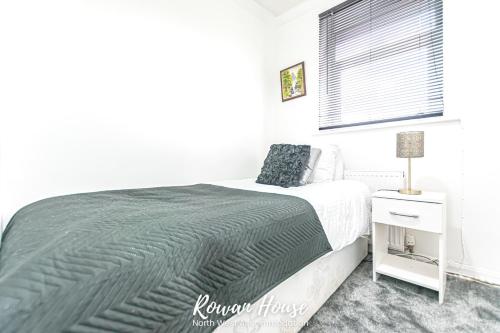 um quarto com uma cama grande e uma janela em Rowan Serviced Accommodation em Lowton