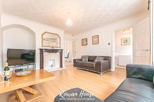 uma sala de estar com um sofá e uma televisão em Rowan Serviced Accommodation em Lowton