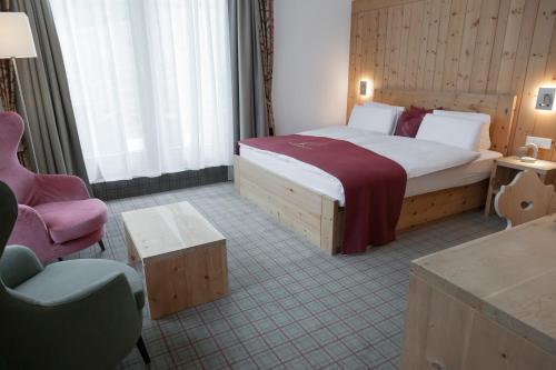 a hotel room with a bed and a chair at Hotel Baer & Post Zernez in Zernez