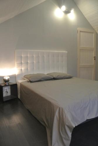 - une chambre avec un grand lit et une tête de lit blanche dans l'établissement Gite de Charme, à Villeneuve-sur-Auvers
