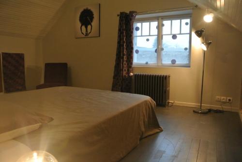 um quarto com uma cama grande e uma janela em Gite de Charme em Villeneuve-sur-Auvers