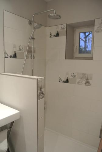 une salle de bain blanche avec une douche et un lavabo dans l'établissement Gite de Charme, à Villeneuve-sur-Auvers
