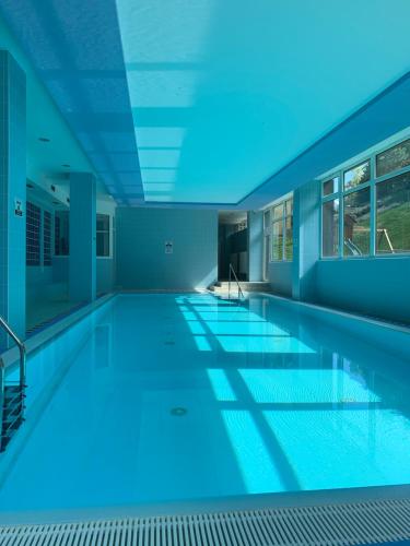 a large swimming pool with blue lighting in a building at Horský hotel Jelenovská s bazénem v ceně in Valašské Klobouky