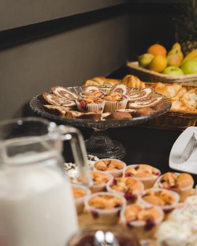 a table topped with trays of pastries and fruit at Hotel Resurs in Podgorica