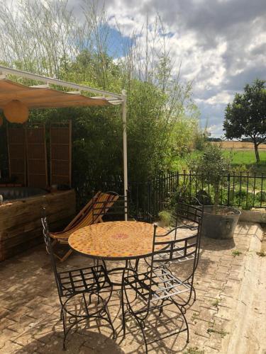 una mesa y sillas bajo una sombrilla en un patio en Chez Vincent et Myriam gîte de charme, en Aussonne
