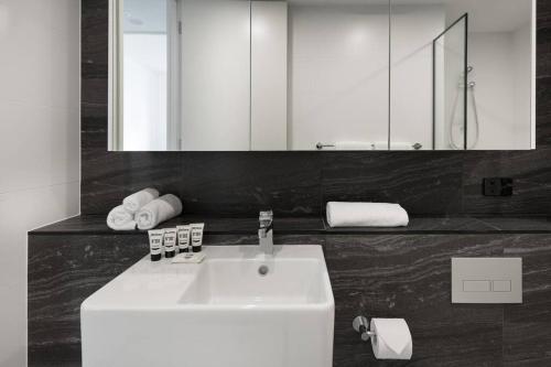 a bathroom with a white sink and a mirror at Luxury 2 bed short walk Sydney Convention Centre in Sydney