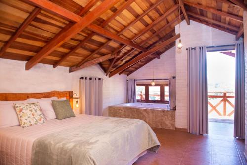 a bedroom with a bed and a large window at Pousada Alpes da Mantiqueira in Monte Verde