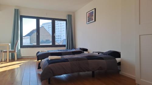 a bedroom with two beds and a large window at BOHO studio Center of Antwerp in Antwerp