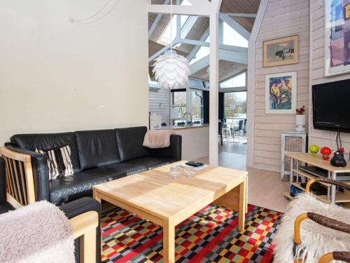 a living room with a black leather couch and a table at 6 person holiday home in Vemb-By Traum in Vemb