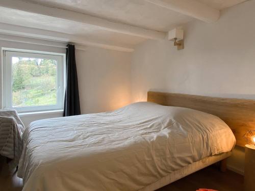 a bedroom with a white bed with a window at Gîte Les Ebeteux in Fraize