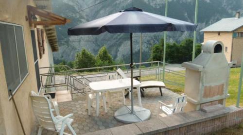 een patio met een tafel en een parasol bij La Bergerie in Condamine-Châtelard