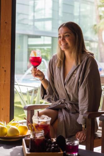 a woman sitting in a chair holding a glass of wine at Oassium Hotel - Adults Only in La Pineda