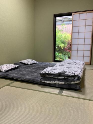 翠云間 庭院式京町屋 京都四条西院 في كيوتو: سرير كبير في غرفة مع نافذة