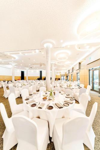 a banquet hall with white tables and white chairs at WENS Hotel in Mainz