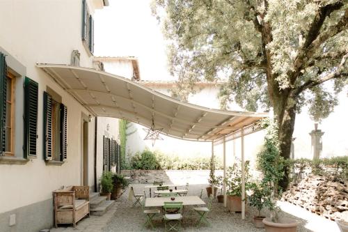 un patio con mesas de picnic y un árbol en Villa de' Ricci Rignana di Sveva Rocco di Torrepadula en Greve in Chianti