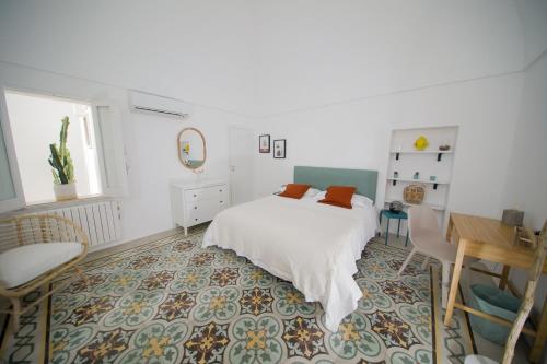 a bedroom with a white bed and a table and a chair at CASA RICASOLI by MANZONI COLLECTION in Monopoli
