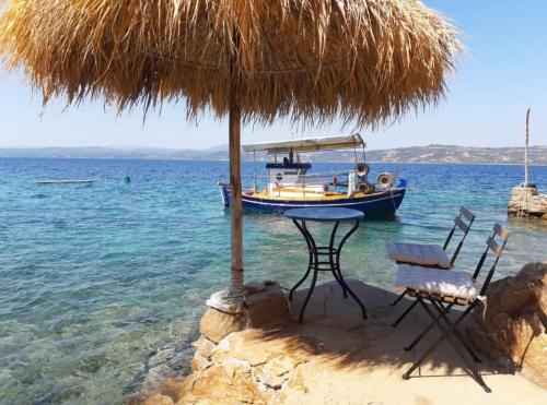 a table and chairs on a beach with a boat at Ammou Area in Ammouliani