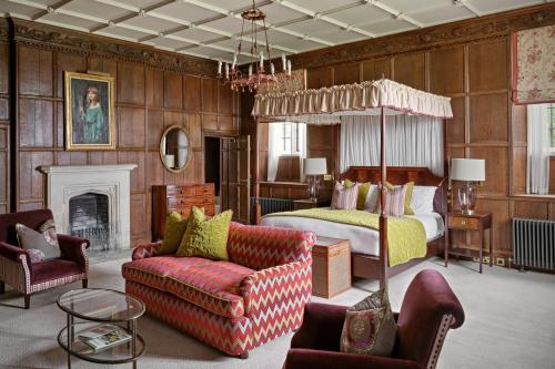 a bedroom with a bed and a couch and a chair at Ellenborough Park in Cheltenham