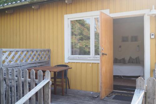 a porch with a table and a window and a bed at Brukshotellet Öland - kursgård och vandrarhem in Degerhamn