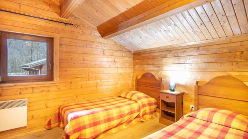 a bedroom with two beds in a wooden cabin at Bois de Champelle - 14 - Chalet cosy - 6 pers in Morillon
